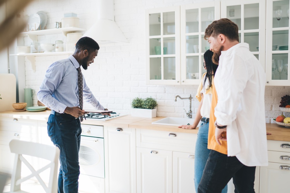 First-time home buyer realtor in Berkeley guiding couple through kitchen tour